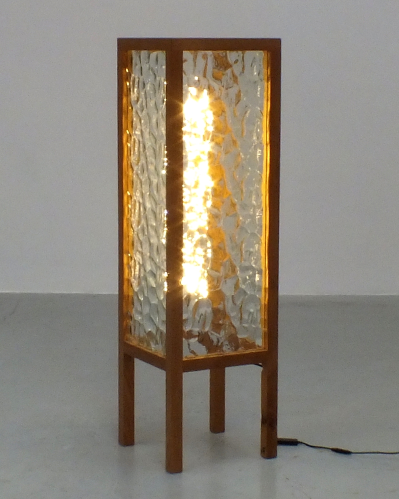 A handcrafted lamp made from reclaimed rippled glass and oak spindles