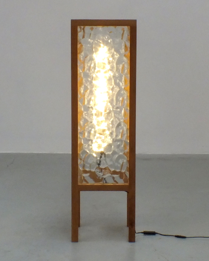 A handcrafted lamp made from reclaimed rippled glass and oak spindles